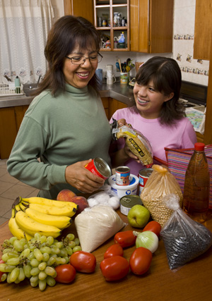 a mother and daughter sorting food on the kitchen counter